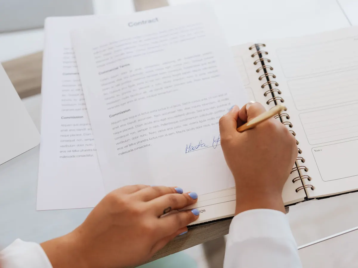 Persona firmando un contrato sobre un escritorio